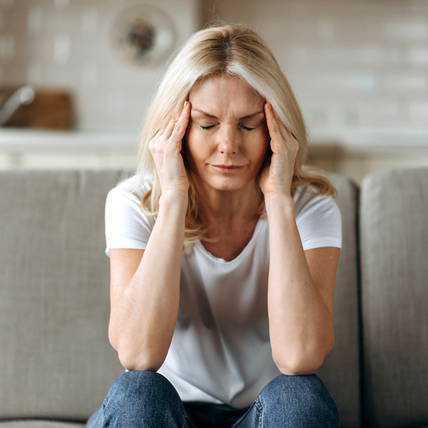 woman with hands on side of head from headache pain